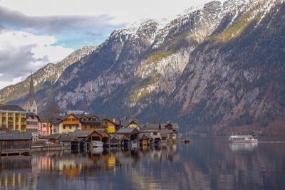 Houses by lake and mountains against sky