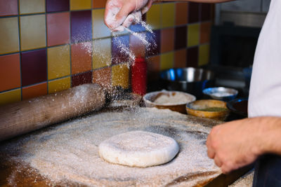 Midsection of man preparing dough in kitchen