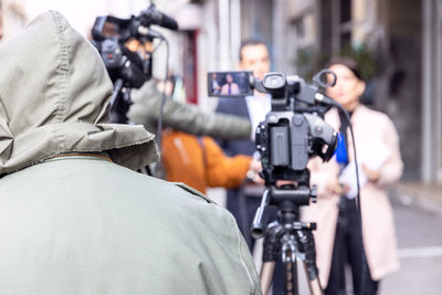 Rear view of man photographing woman in city