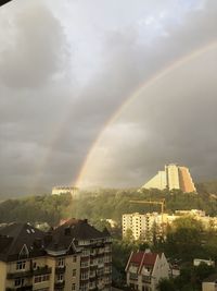 Rainbow over buildings in city against sky