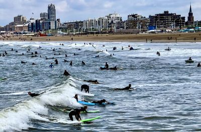 People in sea by city against sky