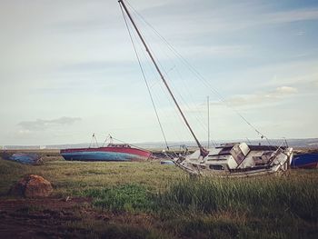 Boats moored on field against sky