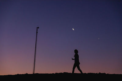 Silhouette man standing on field against sky at sunset