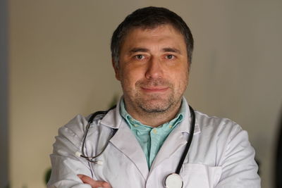 Portrait of smiling mature doctor against wall