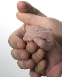 Cropped image of parents and baby holding hands against white background