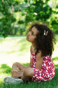 Side view of young woman sitting on field