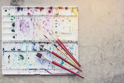 Directly above shot of paintbrushes and palette on table