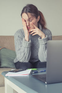 Midsection of woman using phone while sitting on table