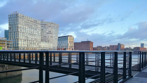 Modern buildings by river against sky in city