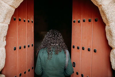 Rear view of woman entering through door of historic building 