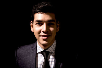 Portrait of young businessman against black background