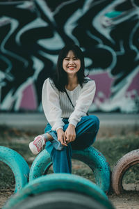 Portrait of a smiling young woman sitting outdoors