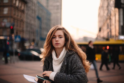 Portrait of young woman using phone in city