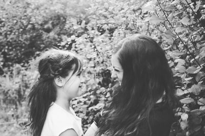 Smiling mother and daughter against plants