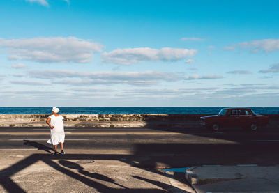 Rear view of man on beach against sky