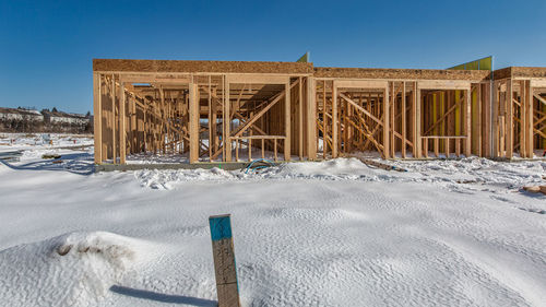 Built structure on snow covered land against clear blue sky