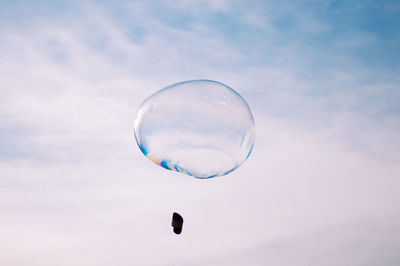 Low angle view of kite flying against cloudy sky