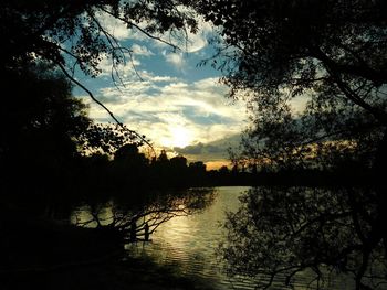 Silhouette trees by lake against sky during sunset