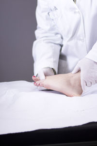 Midsection of doctor examining patient barefoot in hospital