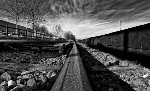 Railroad tracks amidst bare trees against sky