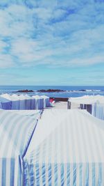 Hooded chairs on beach against sky