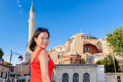 Portrait of smiling woman against mosque in city