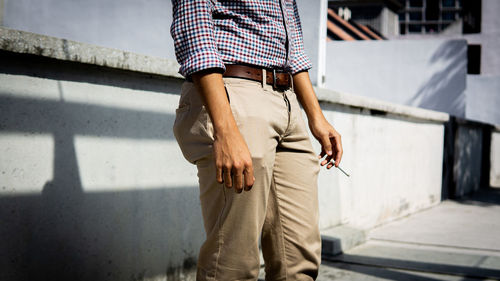 Midsection of man standing against railing in city