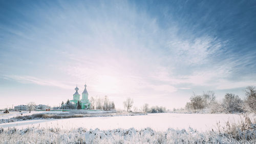 Snow covered field against sky during sunset