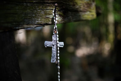Close-up of cross hanging from nail on wood