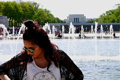 Young woman standing by fountain against lincoln memorial