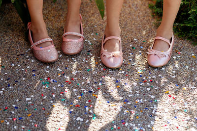 Low section of female friends wearing shoes while standing on colorful confetti