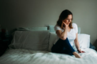 Woman sitting on bed at home