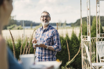 Happy mature man smiling at female friend in back yard