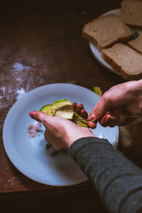 Midsection of person holding fruit in plate on table