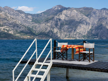 Chairs and table by sea against mountains