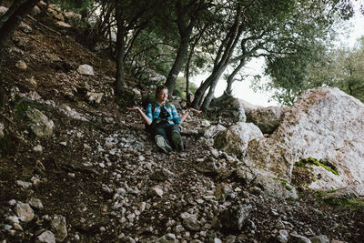 Man sitting on rock in forest