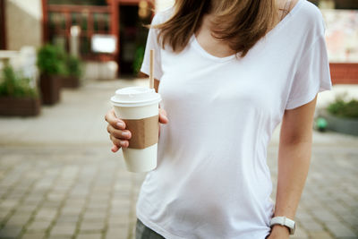 Woman holds paper coffee cup at city street