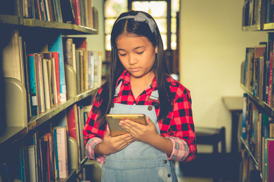 Girl using digital tablet in library