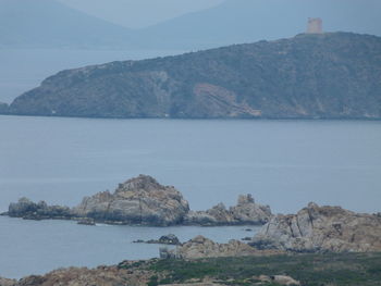 Scenic view of rocks in sea against mountains