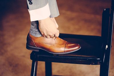 Low section of man tying shoe on chair
