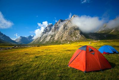 Scenic view of tent on mountain against cloudy sky