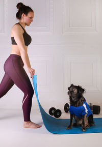 Sport with a dog. attractive girl working out on the blue fitness mat with her dog. athletic woman