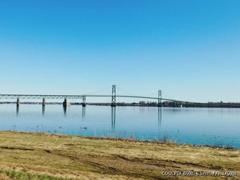 Bridge over river against clear blue sky