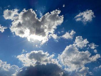 Low angle view of sunlight streaming through clouds