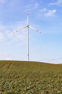 Low angle view of windmill against sky and wind turbine