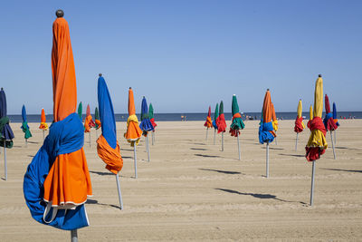 Rear view of people on beach against clear sky