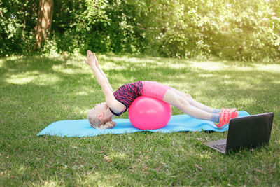 Girl child doing distant remote sport workout outdoor online. video yoga stretching on internet. 