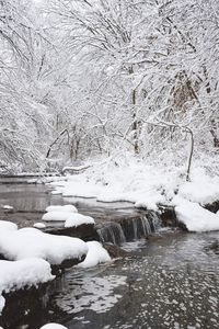 Snow covered stream against sky during winter