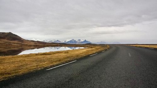 Empty road amidst landscape against sky