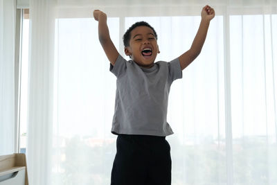 Full length of a boy standing by window